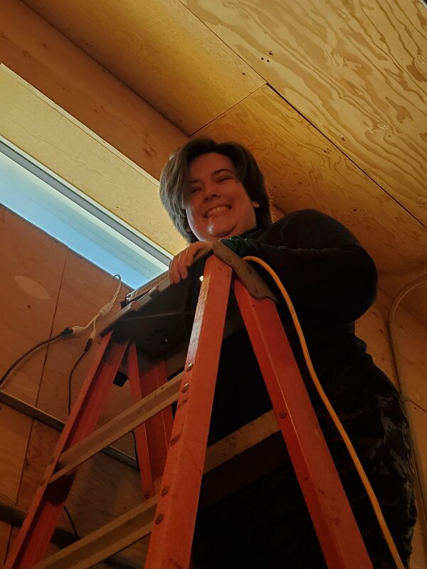 Darby using a ladder to put up a camera